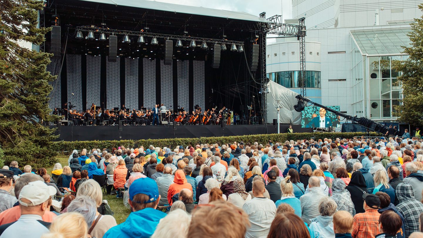 mainoskuva Puistokonsertti 2022 ilmaistapahtumasta Tampereen Sorsapuistossa, jossa on iso esiintymislava ja yleisöä