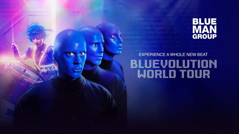 Kolme sinipäistä miestä tuijottavat eteenpäin, taustalla naisrumpalin hahmo.