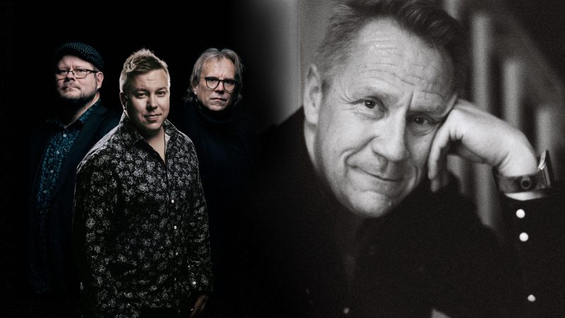 Kolme esiintyjää seisovat lähekkäin kuvan vasemmassa reunassa ja säveltäjä Olli Lindholm kuvan oikealla puolella nojaa kädellä kasvoihinsa.