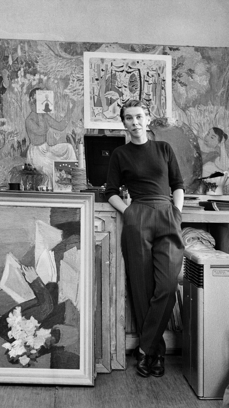 Taiteilija Tove Jansson seisoo ateljeessaan vanhassa musta-valko valokuvassa.