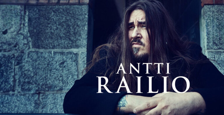 Antti Railio nojaamassa kaiteeseen. Taustalla kiviseinä.