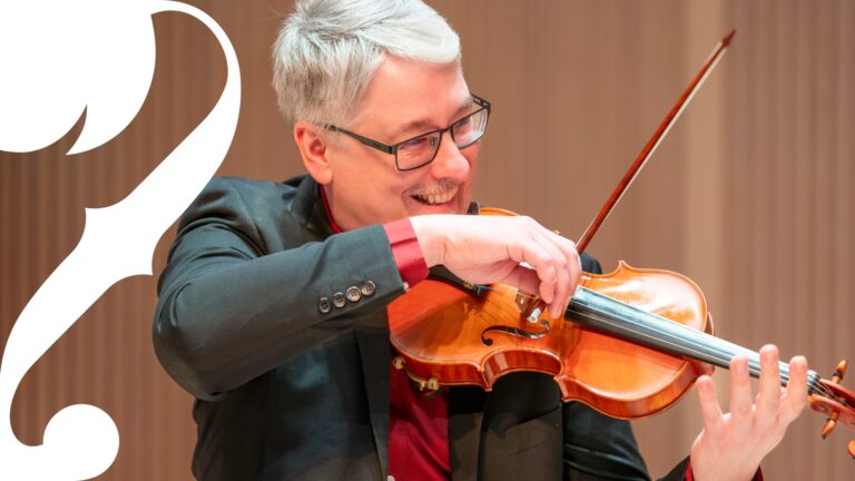 Man playing violin with smile on his face.