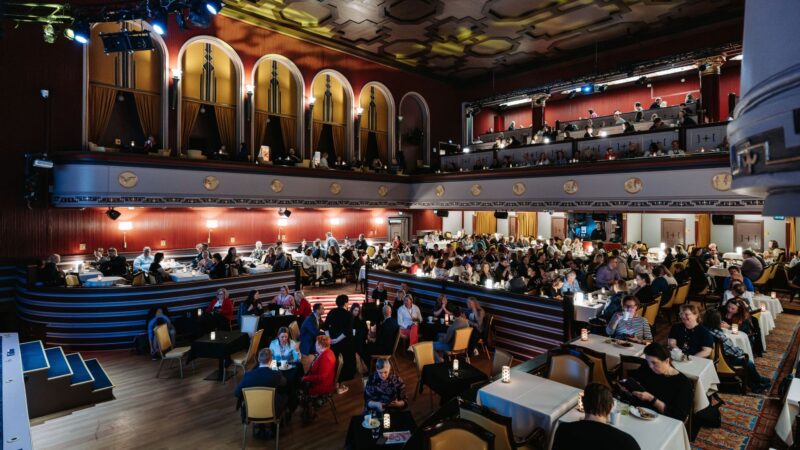 Tuulensuu Palaces main hall filled with Monetra staff day participants seated at tables, following the program on stage.
