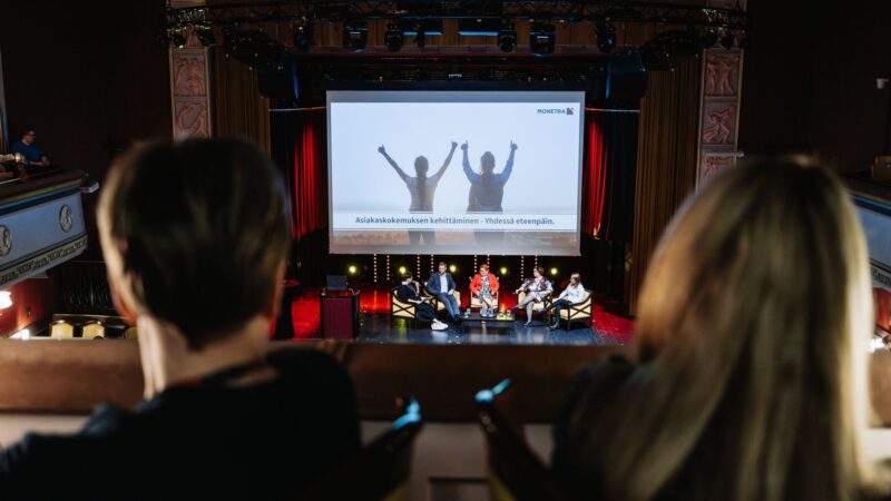 View from the Tuulensuu Palace balcony towards the stage during a panel discussion on customer experience.