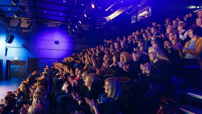 Talo Evenstin tapahtumapalveluiden tilaisuudessa yleisö taputtaa Tampere-talon Maestro salin katsomossa