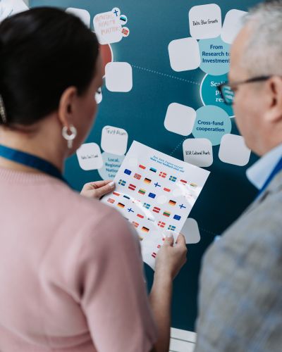 Talo Eventsin tapahtumapalveluiden kongressitoimiston tapahtumassa kaksi henkilöä tutkii paperia lähietäisyydellä